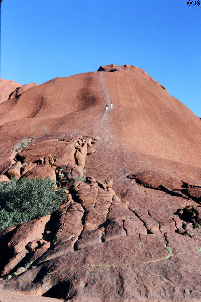 Hikers make climb up Uluru (aka Ayers Rock) even though aboriginals ask them not to because the mountain is sacred. Australia.