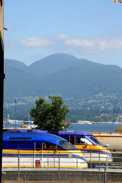 Westcoast Express locomotives before harbour & North Vancouver mountains. Vancouver, BC.