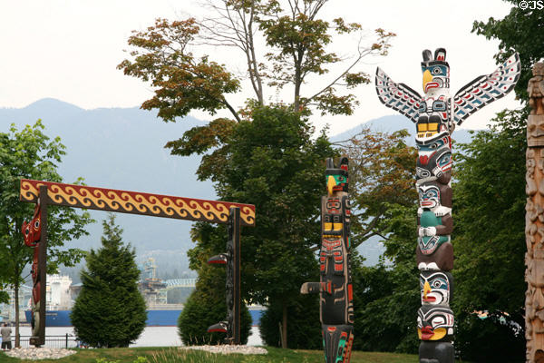 Northwest coast native totem poles in Stanley Park against mountains. Vancouver, BC.