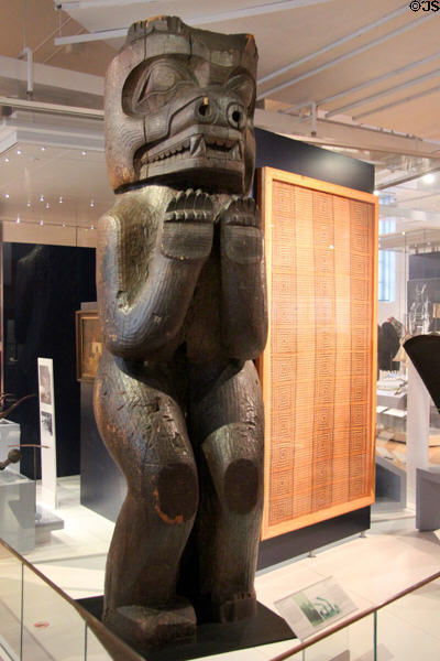 Rivers Inlet carved cedar house post (late 19thC) representing bear beside Haida Gwaii woven cedar mat (early 20thC) at Royal Ontario Museum. Toronto, ON.
