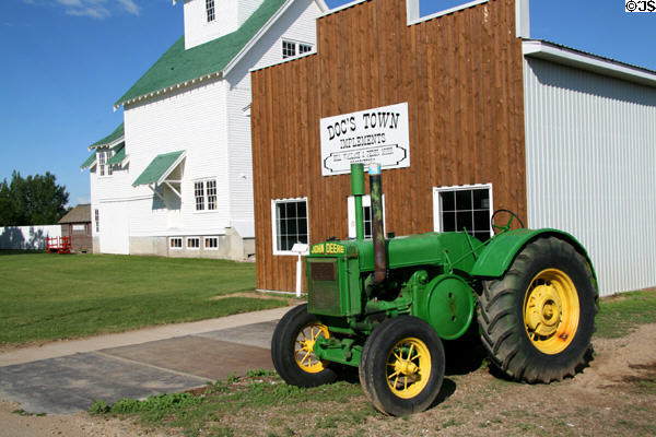 Antique rubber-tired John Deere D tractor (1936) in front of Myhr & Wallace Implements board & batten building at Doc's Town. Swift Current, SK.