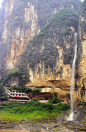 Water fall and building along gorge walls of Yangtze River. China.