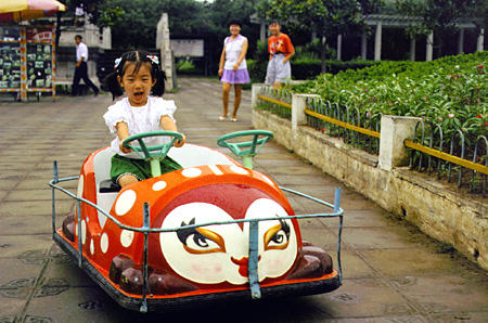 Child drives a kiddie car in Yichang. China.