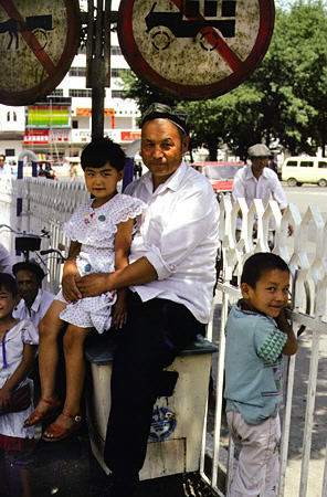 Father sits with his children in Urumqi (Urumchi). China.