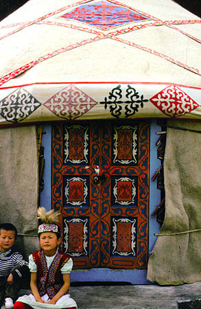 Children sit in front of a yurt in Uighur village near Urumqi. China.
