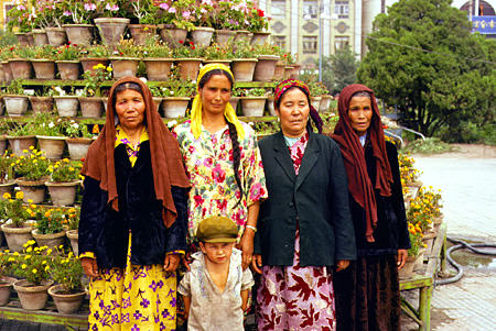 Women from Kashgar pose in front of potted flowers. China.