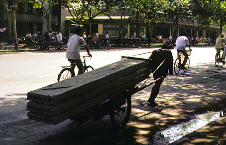 Man-powered cart pulling concrete beams along a street in Hangzhou. China.