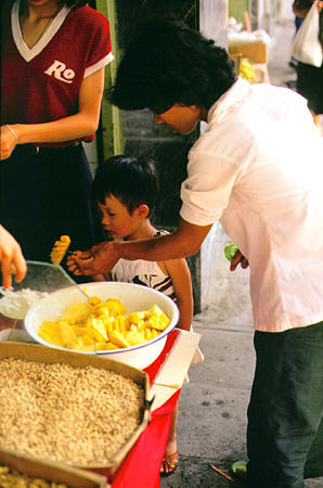 Child eating pineapple pieces in Guangzhou. China.