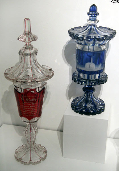 "Birthday Club" lidded glass goblet partly covered in red (1860) & Cup partially covered in blue. In the image field you can see the cut view of the Michaeliskirche with the signature, St Michaeliskirche at Hamburg History Museum. Hamburg, Germany.