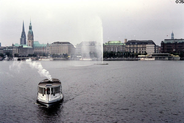 Fountain in Binnenalster Lake with Germany's oldest steamboat, St Georg, providing a tourist cruise. Hamburg, Germany.