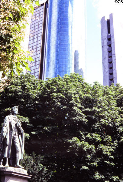 Statue of Friedrich von Schiller holding pen & book (1864) by Johannes Dielmann with skyscrapers in background in Taunusanlage. Frankfurt am Main, Germany.