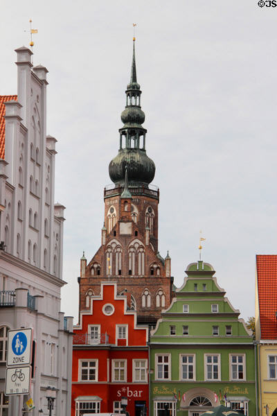 Germanic market buildings with St Nicholas Church tower beyond. Greifswald, Germany.