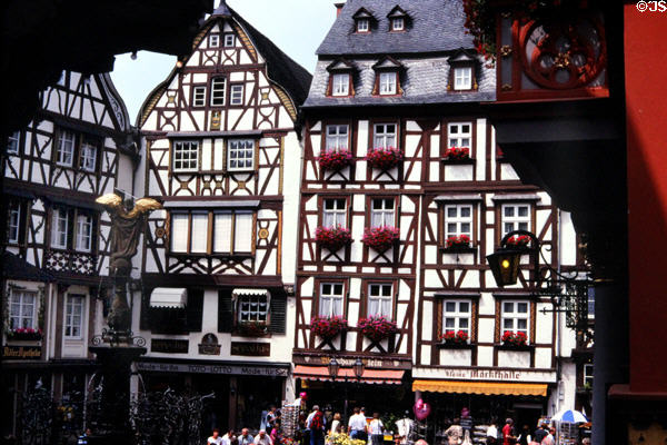 Row of half-timbered buildings in market square with fountain topped by statue of St Michael wielding his sword (c1950, original destroyed WWII). Bernkastel-Kues, Germany.