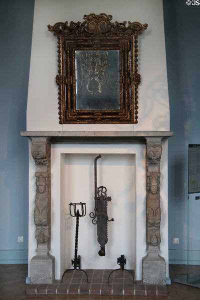 Mirror over carved fireplace mantle with andirons & adjustable pot hanger in Blue Hall at Gottorf Palace. Schleswig, Germany.