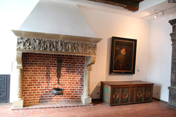 Carved chimney lintel (early 17thC) with iron Pothook (1769) holding bronze cooking pot (1580) beside portrait over medallion chest (mid 16thC) at Schleswig Holstein State Museum. Schleswig, Germany.