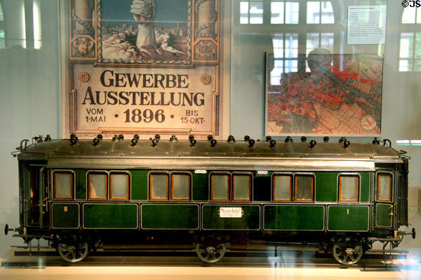Model of Bavarian passenger wagon (1897) under poster of Berlin Trade Show (1896) at Nuremberg Transport Museum. Nuremberg, Germany.