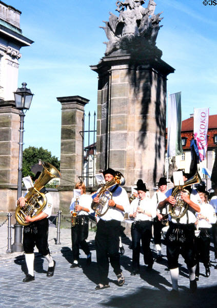 Town brass band passes through gates beside Residenz. Ansbach, Germany.