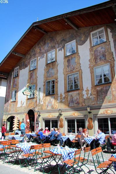 Traditional hotel & restaurant with elaborate sign and exterior wall filled with paintings. Mittenwald, Germany.