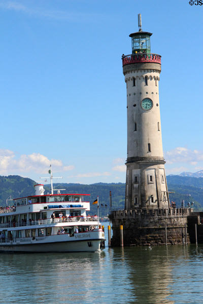 Sightseeing boat passing lighthouse (1856) at harbor entrance. Lindau im Bodensee, Germany.