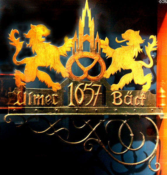 Colored wrought iron sign (c1900) for Ulm bakery with profile of Ulm Cathedral & two lions holding pretzel at Museum of Bread and Art. Ulm, Germany.