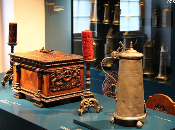 Display of metal flask, candlestick & ornately carved wooden box related to bakers & guilds at Museum of Bread and Art. Ulm, Germany.