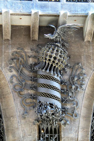 Decoration of bird atop crown atop spiral pole between entrance doors at Palau Güell. Barcelona, Spain.