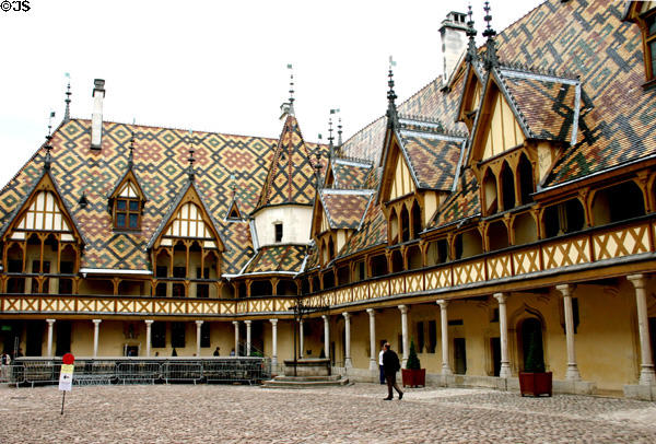 Courtyard of Hotel Dieu (1443) with colored glazed tile roof, gables & finials. Beaune, France. Architect: Jehan Wisecrère.