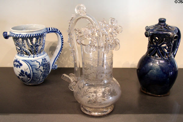 Three puzzle jugs of ceramic (after 1650) from Nevers; glass (18thC) from Bohemia or France; & blue enamelled clay (16thC) from France at Museum of Decorative Arts. Paris, France.
