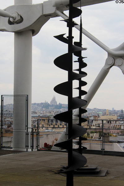 Spiral sculpture on upper deck at Georges Pompidou Center with Sacre Coeur church & Montmartre in distance. Paris, France.