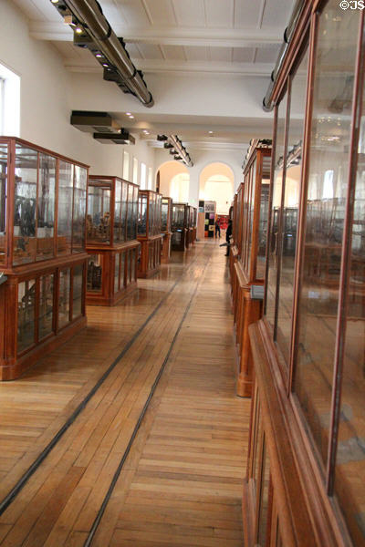 Display cases of early French technology flanking small rail track for moving displays at Arts et Metiers Museum. Paris, France.
