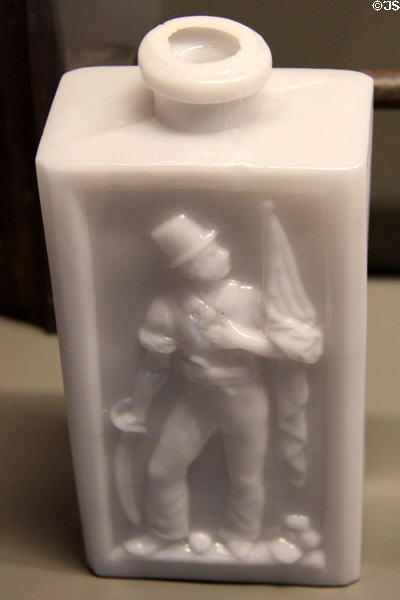 Molded white glass bottle with patriotic figure carrying flag & saber (c1830) at Arts et Metiers Museum. Paris, France.
