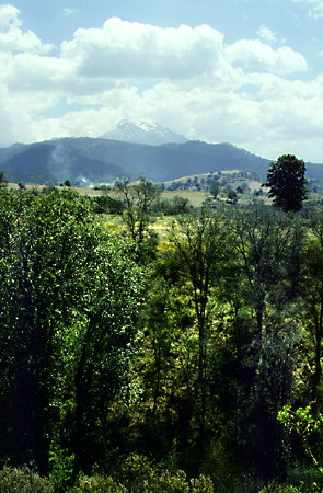 Landscape along route from Mexico City to Puebla with Popocatépetl volcano smoking on horizon. Mexico.