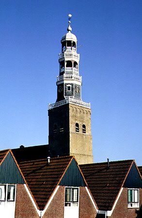 A church tower spires up behind identical houses. Hindeloopen, Netherlands.