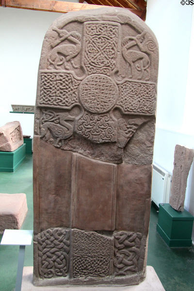 Pictish cross-slab (front of #4) with lacey surface & entwined animals in corners at Meigle Sculptured Stone Museum. Meigle, Scotland.