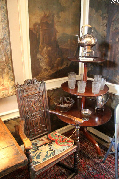 Great chair (1619) beside round tiered table displaying silver & glass items in dining room at Kellie Castle. Pittenweem, Scotland.