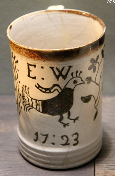 White dipped tankard with scratched bird design filled with brown iron-stained slip (1723) inscribed E:W 17:23 made in North Straffordshire at Potteries Museum & Art Gallery. Hanley, Stoke-on-Trent, England.