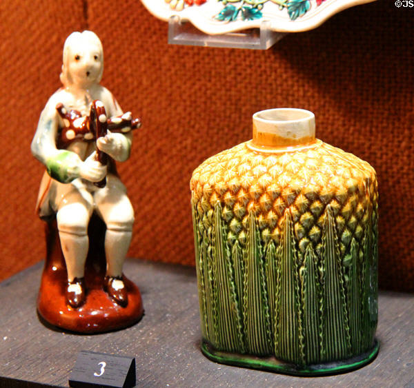 Stained creamware bagpipe player figure (1750-60) & earthenware tea jar in pineapple form with green & yellow glazes (c1760-70) both from Staffordshire at Potteries Museum & Art Gallery. Hanley, Stoke-on-Trent, England.