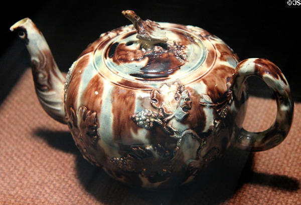 Earthenware teapot with applied molded relief decoration stained with colored oxides under lead glaze (c1750-70) made in Straffordshire at Potteries Museum & Art Gallery. Hanley, Stoke-on-Trent, England.