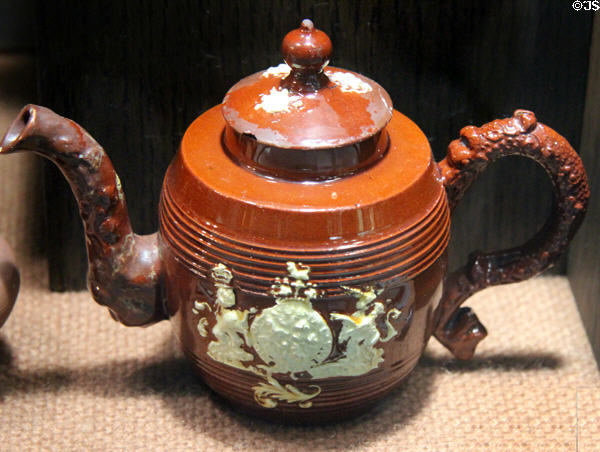 Red earthenware coffee pot with applied molded relief Royal Arms decoration (c1740-60) made in Straffordshire at Potteries Museum & Art Gallery. Hanley, Stoke-on-Trent, England.