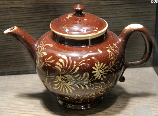 Red earthenware teapot with painted gold decoration (c1750-60) made in Straffordshire at Potteries Museum & Art Gallery. Hanley, Stoke-on-Trent, England.