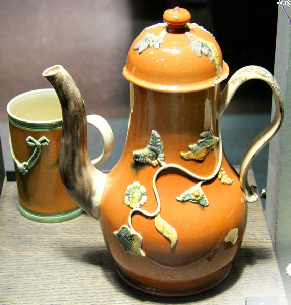 Ochre stained coffee pot & cup with applied molded relief decoration (1750-70) from Staffordshire at Potteries Museum & Art Gallery. Hanley, Stoke-on-Trent, England.