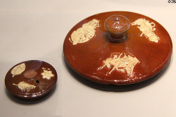 Glazed red earthenware teapot lids with applied white sprigged decoration (applied low relief) (1750-55) a forerunner of Jasperware style at World of Wedgwood. Barlaston, Stoke, England.