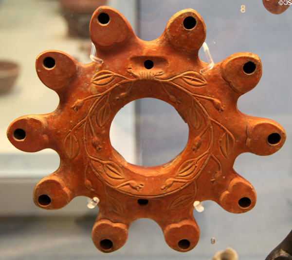 Roman terracotta multi-nozzle ring-shaped oil lamp decorated with myrtle-wreath (c50-100 CE) made in Italy, found in Libya at British Museum. London, United Kingdom.