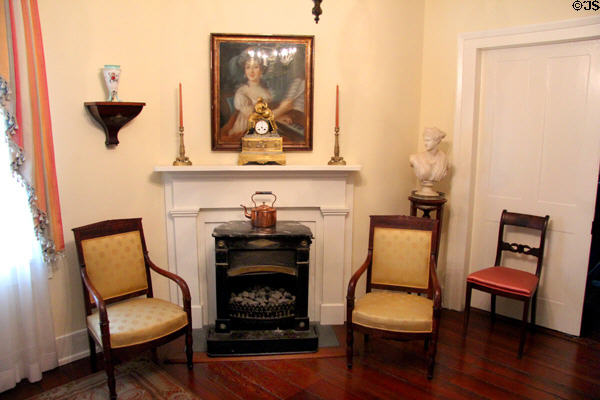 Stove in fireplace with armchairs & mantle clock at Conde-Charlotte Museum. Mobile, AL.