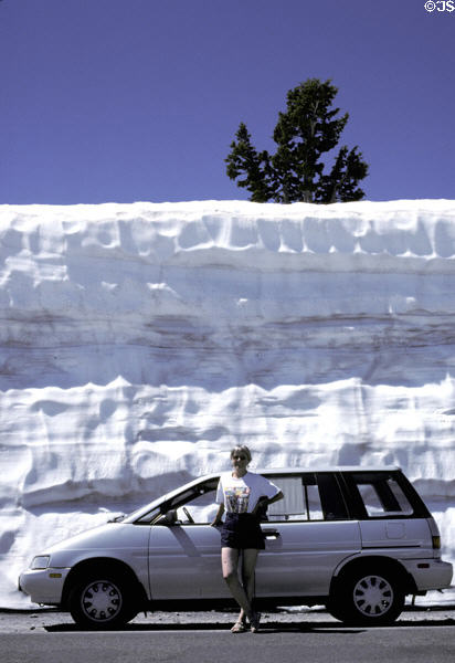 Snowbanks of July tower over cars in highest pass of Lassen Volcanic National Park. CA.