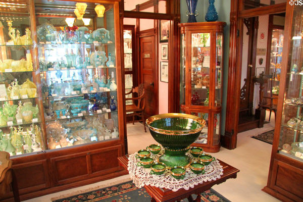Display cases with glass collection around emerald green punchbowl (c1899) by United States Glass Co. of Glassport, PA at Historical Glass Museum. Redlands, CA.