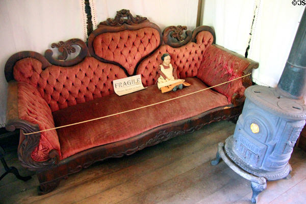 Antique settee with carved wood frame & heating stove in residence part of Wells Fargo office at Columbia State Historic Park. Columbia, CA.