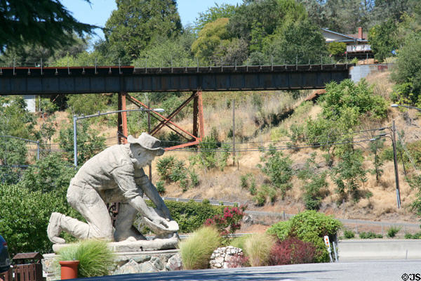 1848 gold discoverer Claude Chana concrete statue (1975) by Dr. Kenneth H. Fox in front of railway bridge across Auburn Ravine. Auburn, CA.
