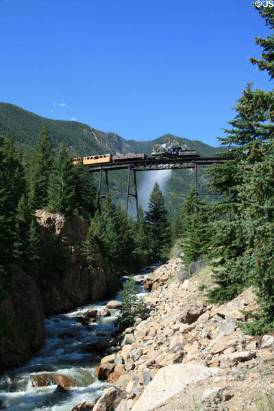 Georgetown Loop Railroad steam train crosses loop bridge above mountain stream. Georgetown, CO.