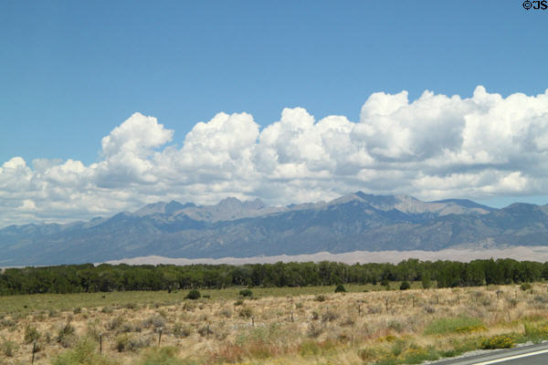 Layers of sky, clouds, mountains, dunes & trees at Great Sand Dunes National Park. CO.